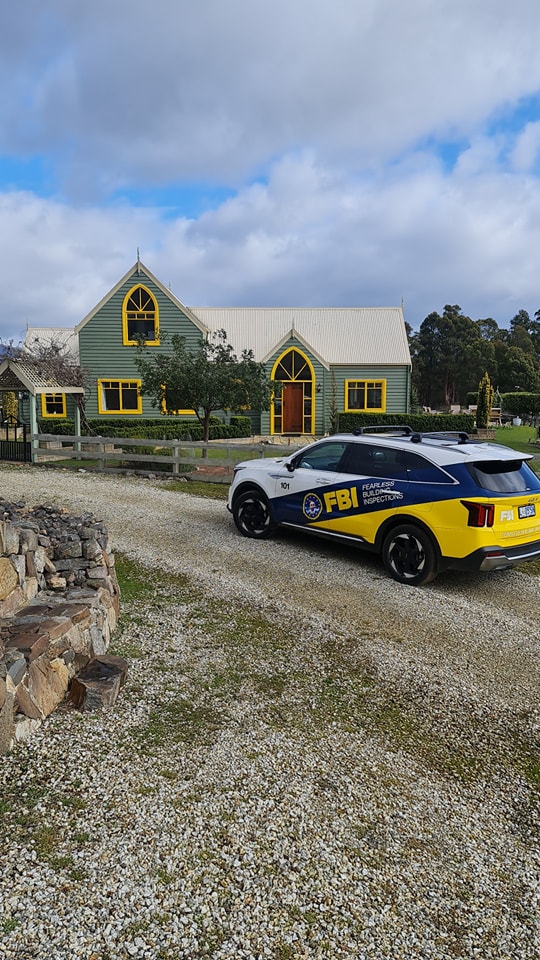 Fearless Building Inspection car parked in front of a green and yellow house