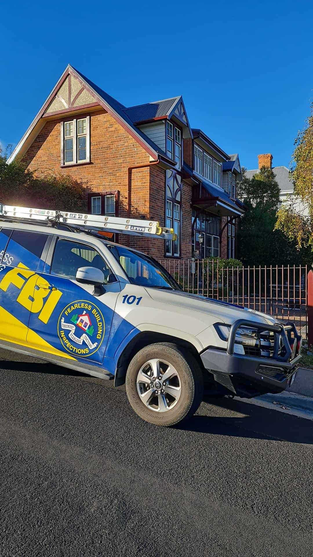 front of a yellow and blue car written FBI parked on the street