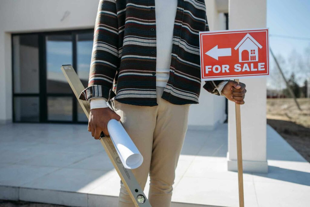 Man holding a house for sale sign