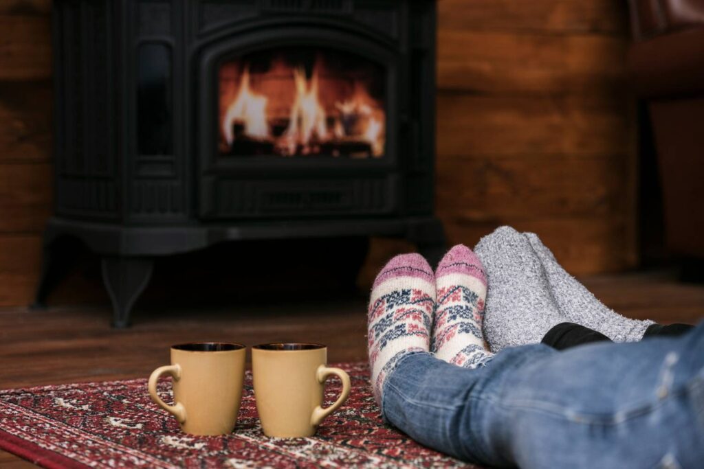 couple heating their feet in front of a fireplace